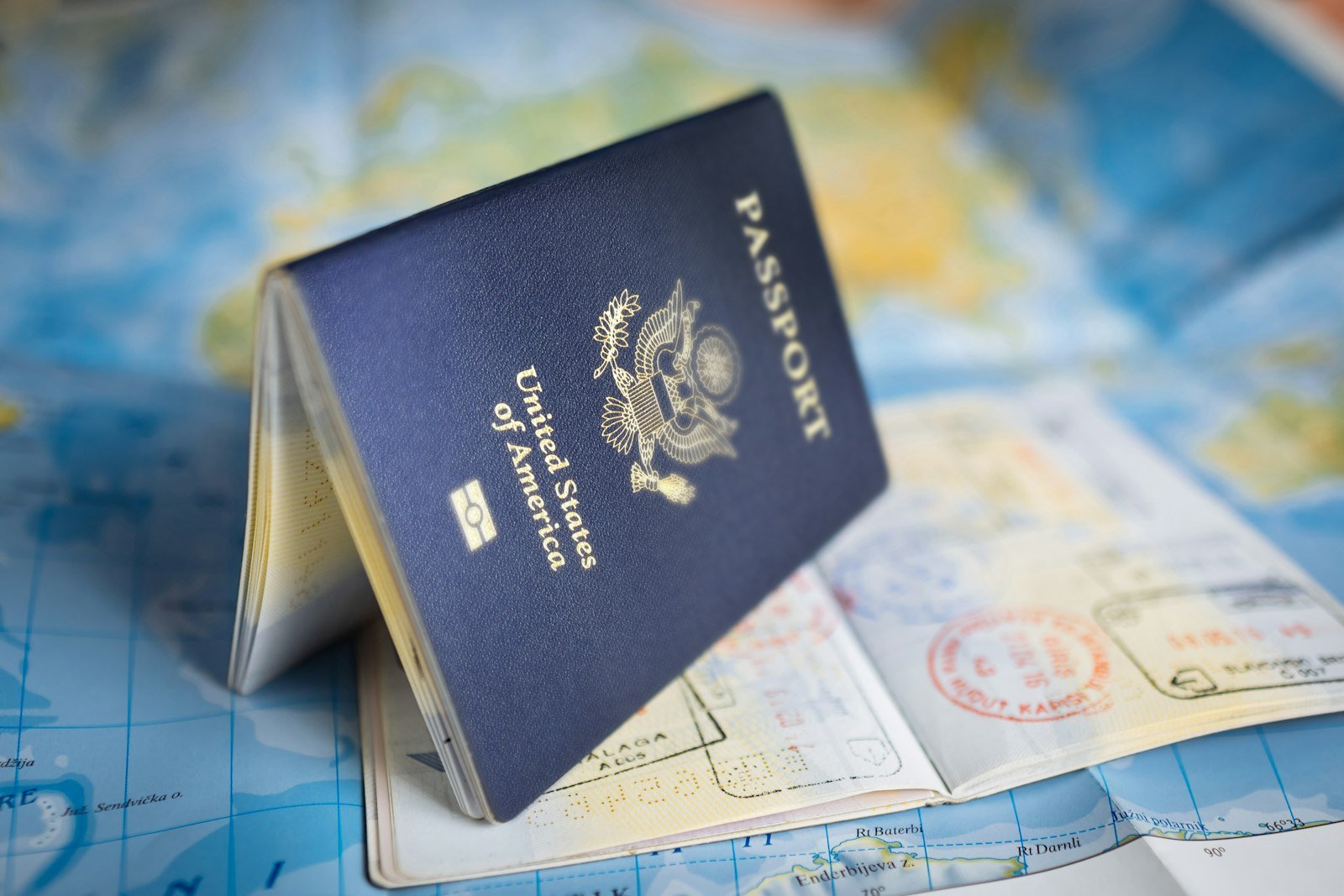 Passport resting open on a colourful world map for international student travel